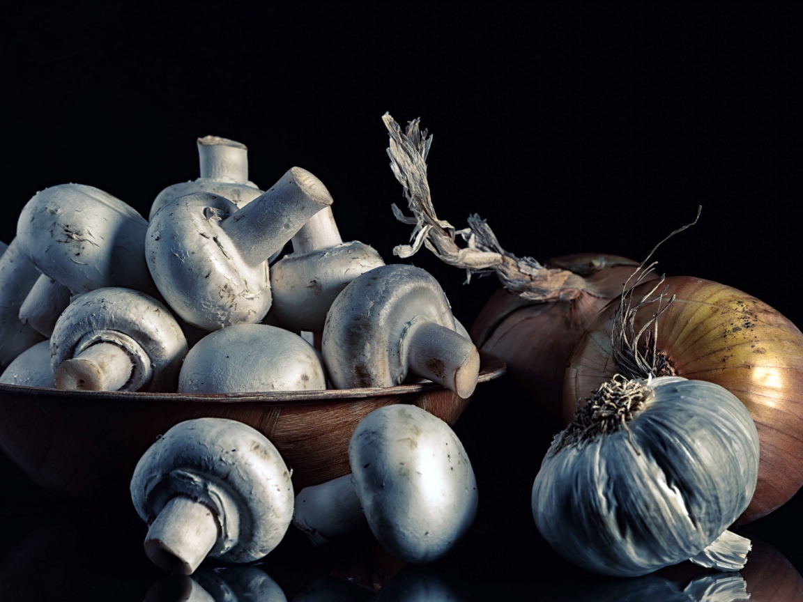 Свежие шампиньоны с луком и чесноком на черном фоне