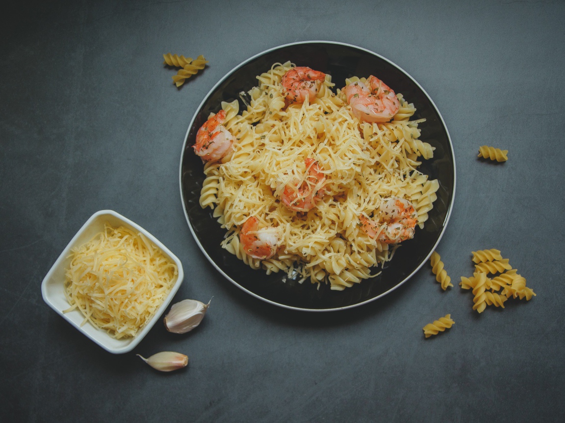 Макароны на тарелке с сыром и креветками