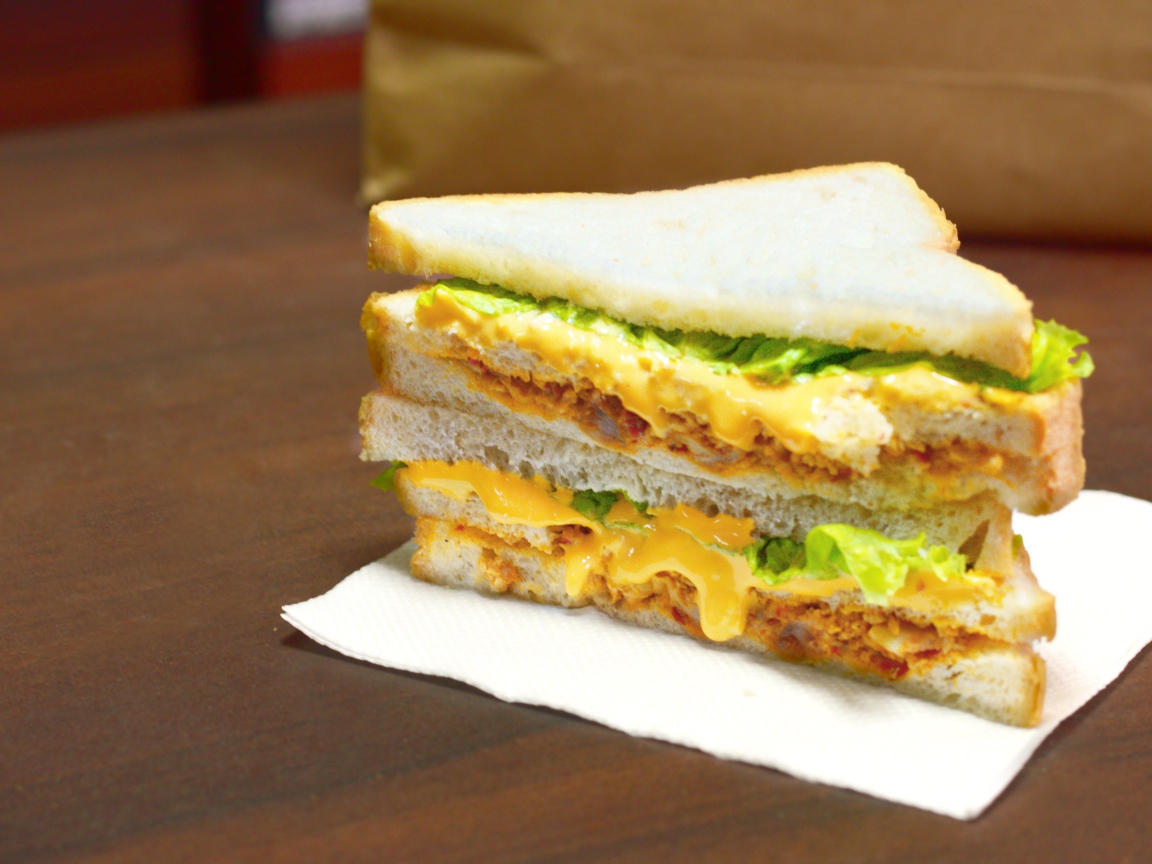 Сэндвич с сыром и листьями салата на столе