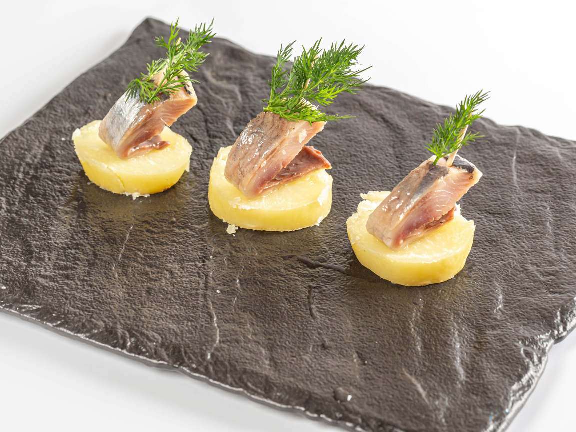 Три куска вареного картофеля с сельдью и укропом