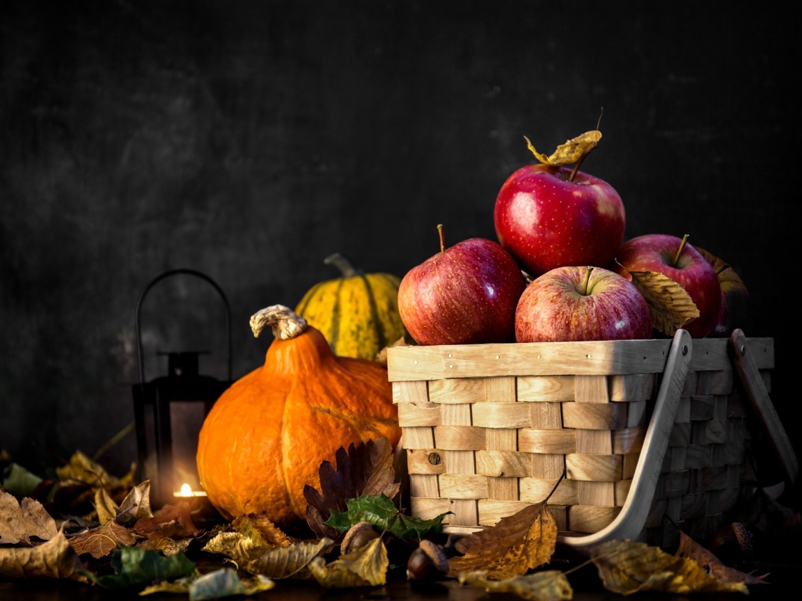 Корзина красных яблок на столе с тыквой