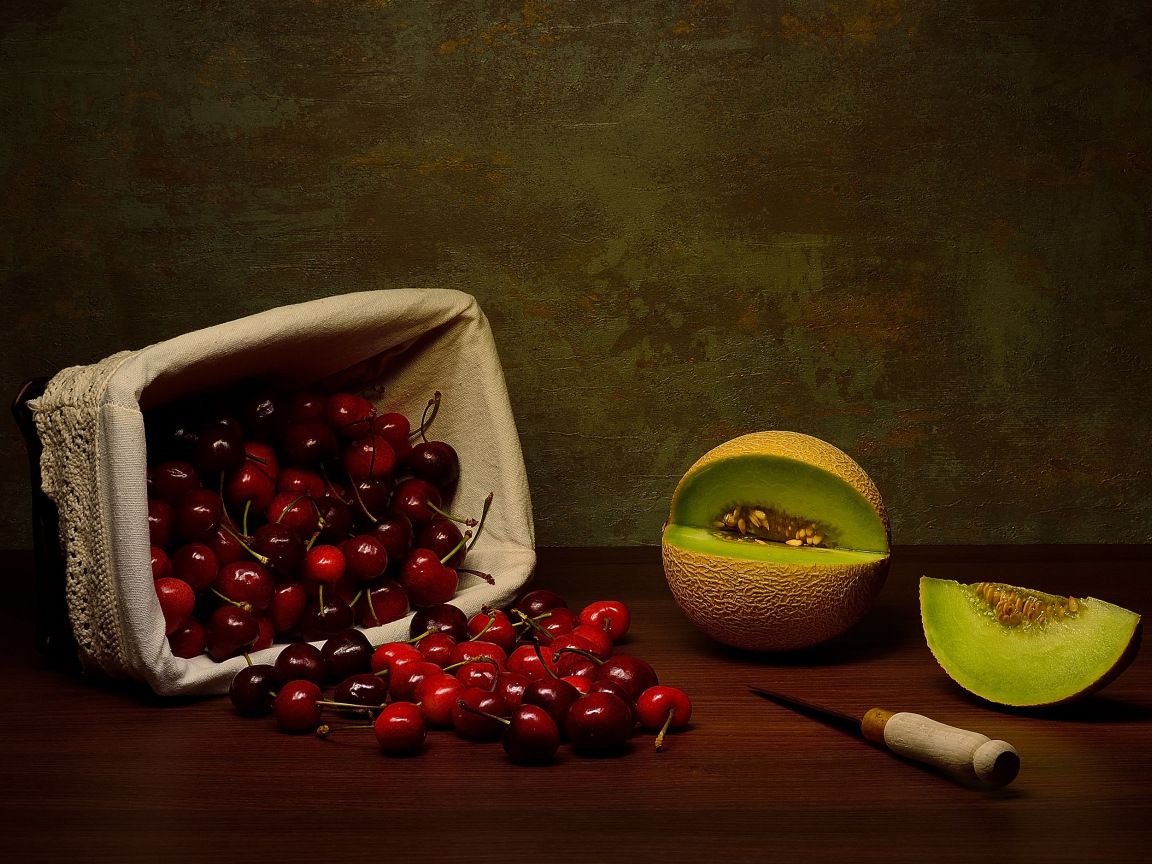 Корзина с черешнями на столе с дыней