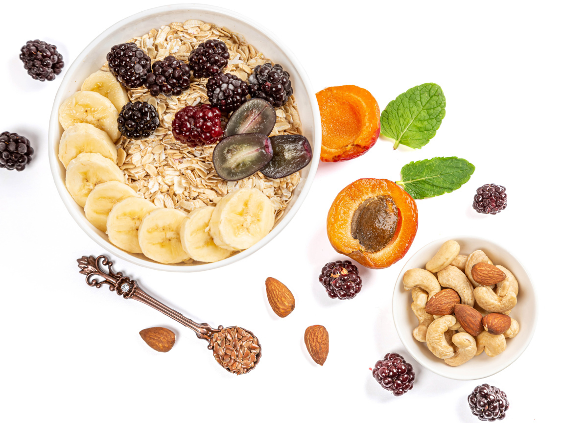 Овсяные хлопья с ягодами и орехами на белом фоне