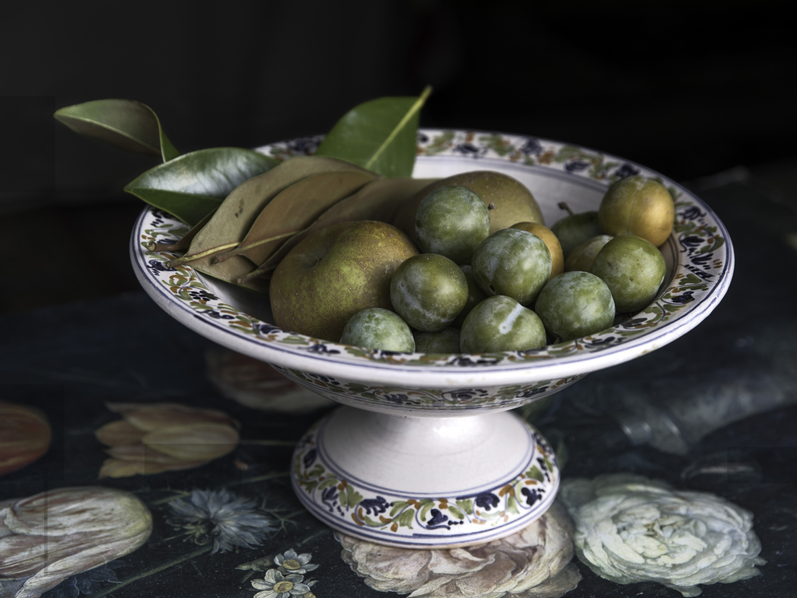 Белые сливы и зеленые яблоки в вазе на столе 