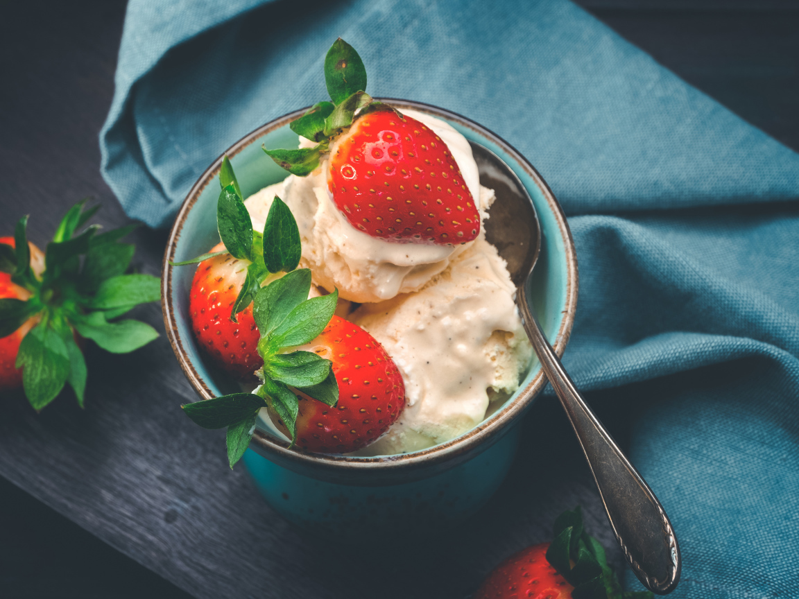 Сливочное мороженое с ягодами клубники в чашке с ложкой