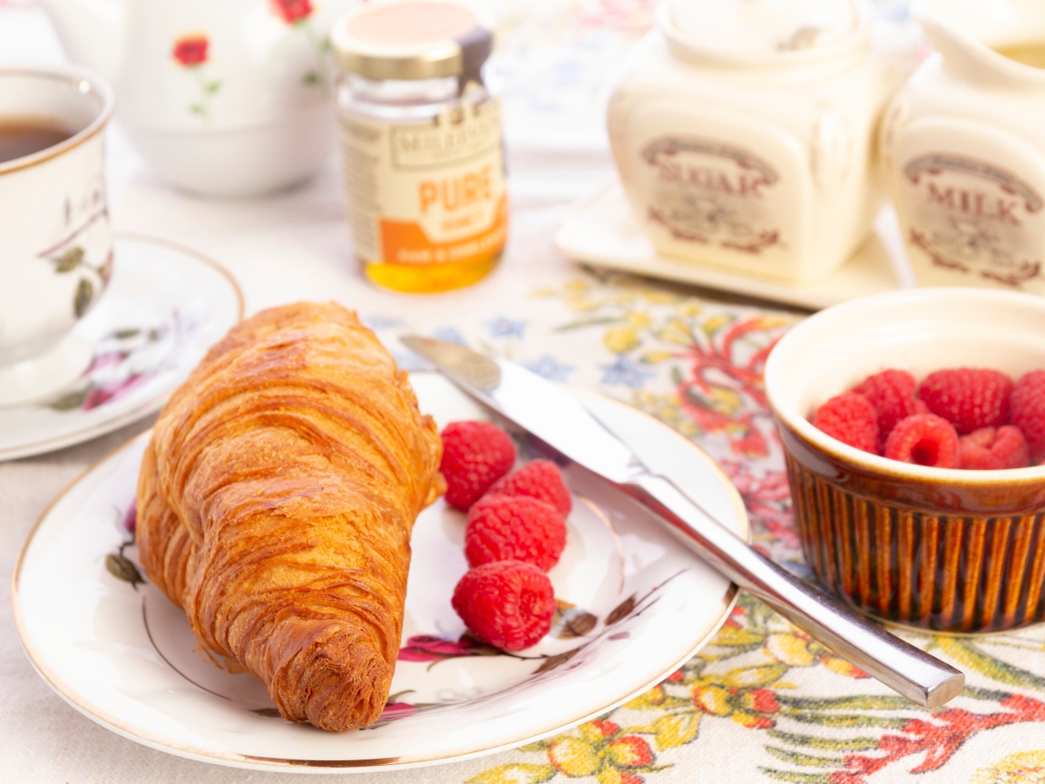 Круассан на тарелке со свежей малиной