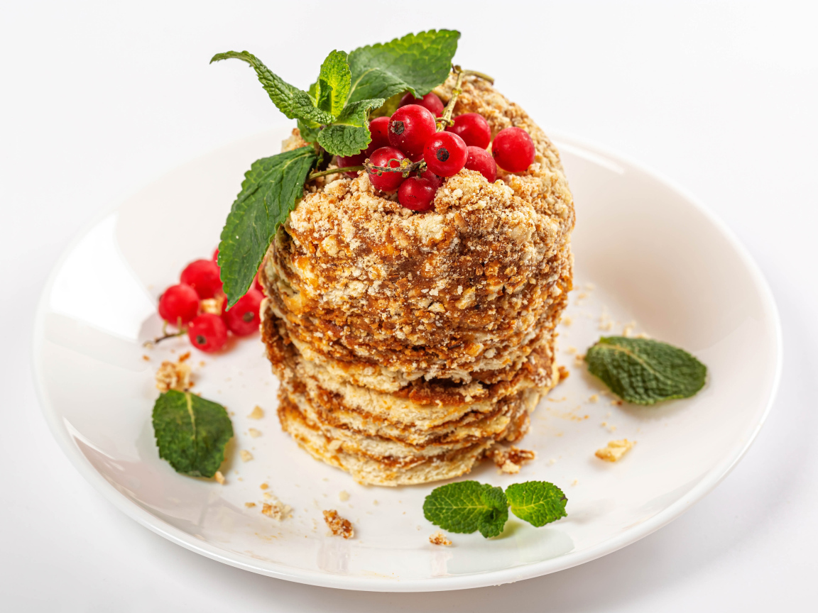 Вкусное пирожное со сгущенкой и ягодами красной смородины на белом фоне