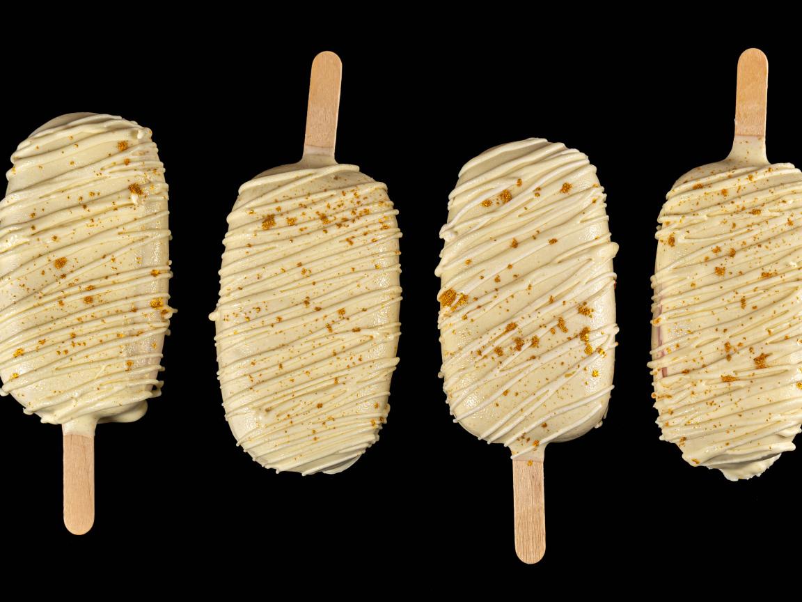 Мороженое на палочке в белом шоколаде на черном фоне