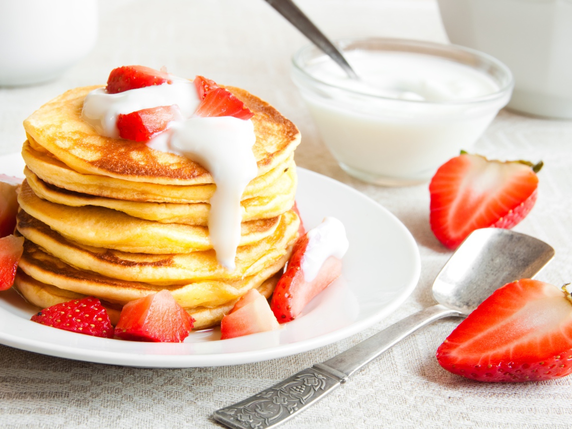 Оладьи с клубникой и сметаной на столе