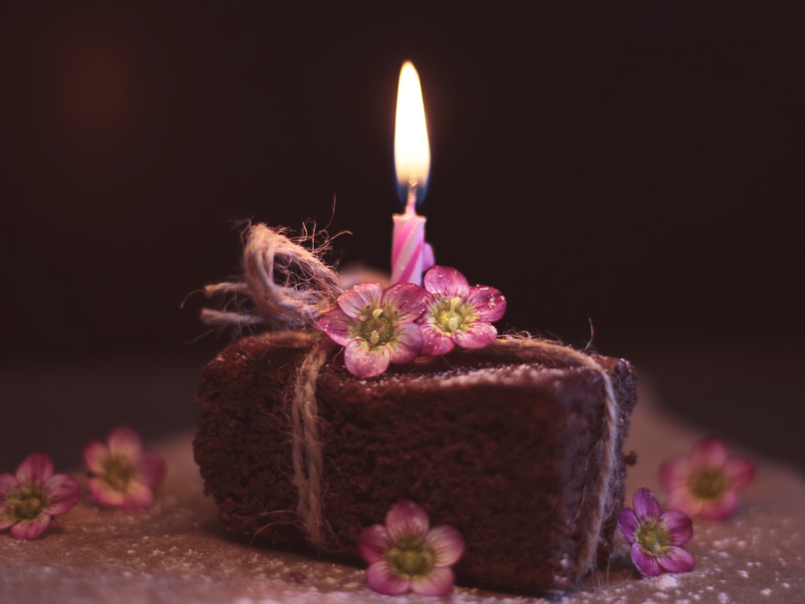 Кусок торта на столе с розовыми цветами и свечкой