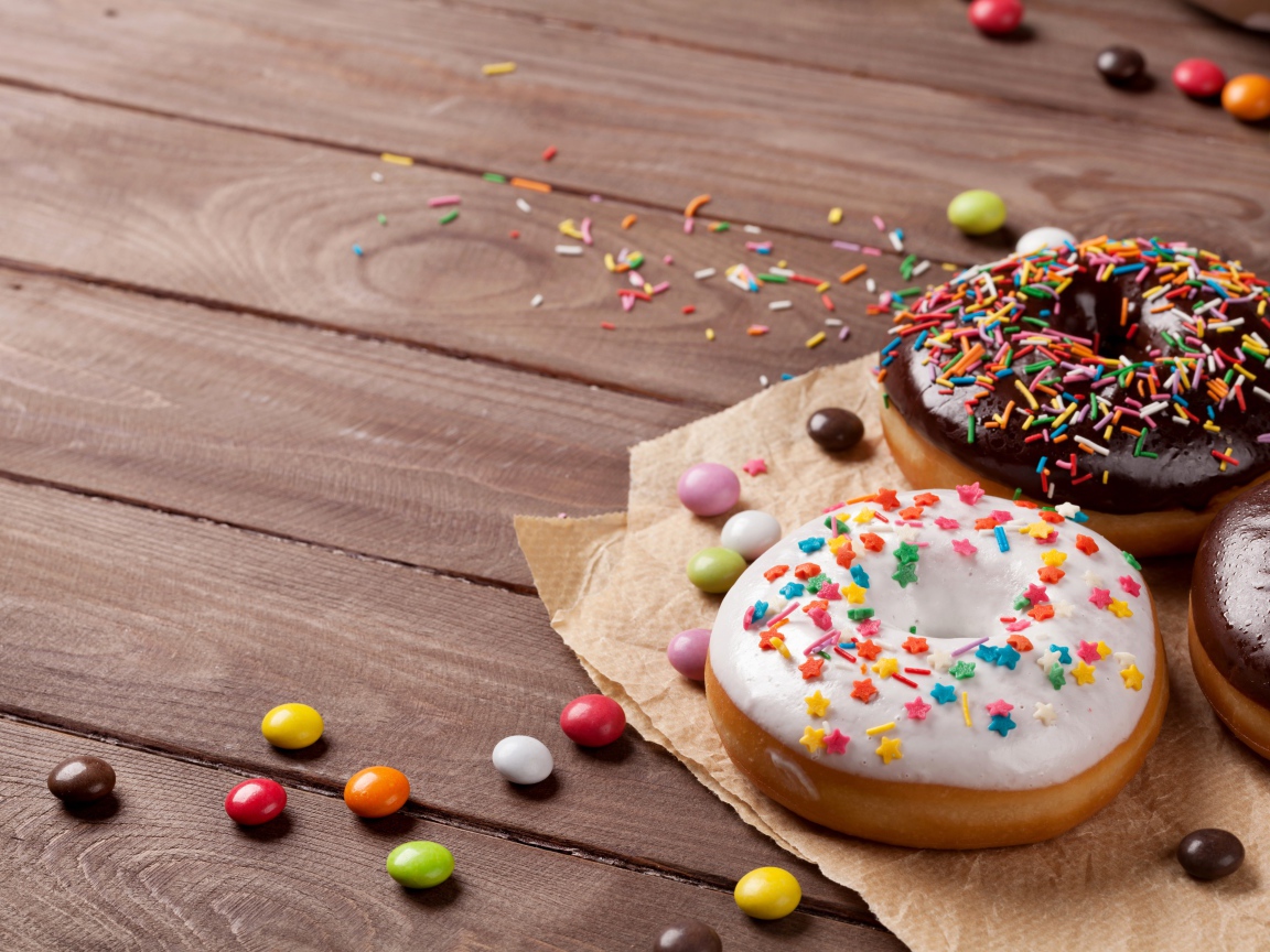 Сладкие пончики с глазурью на столе с конфетами