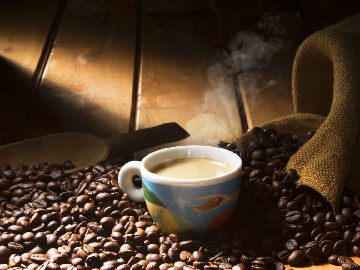 Чашка горячего кофе стоит на зернах