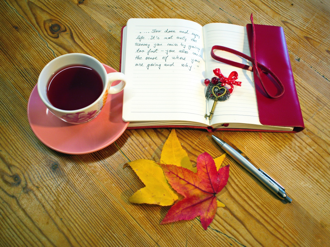 Чашка чая с блокнотом и листьями на столе 