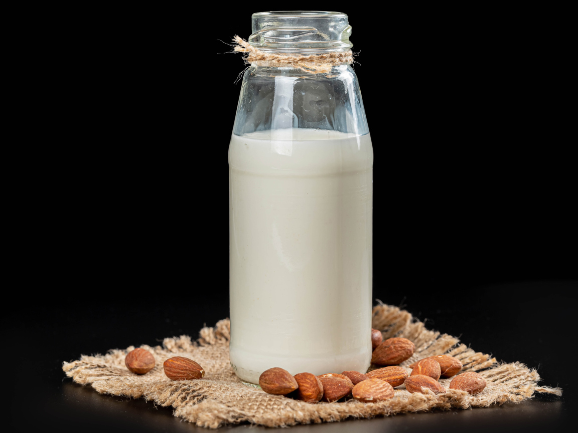 Молоко с миндалем на черном фоне