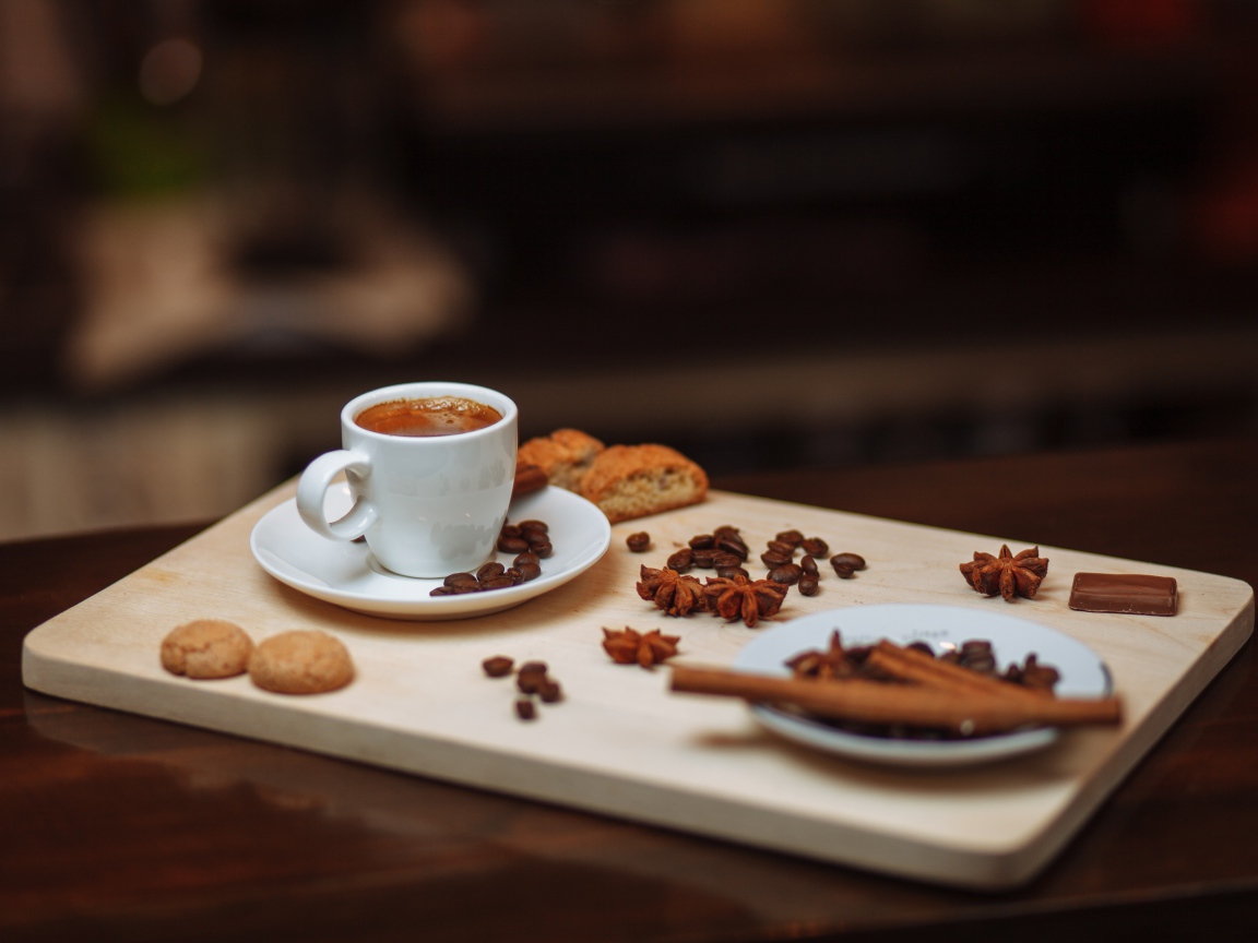 Маленькая чашка кофе на столе с корицей, бадьяном и печеньем 