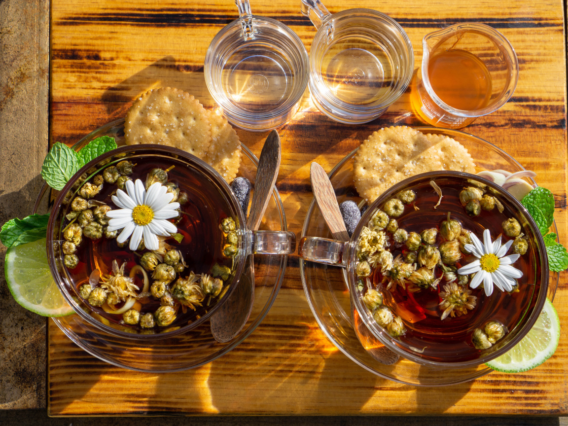 Две чашки чая с ромашкой на столе с медом