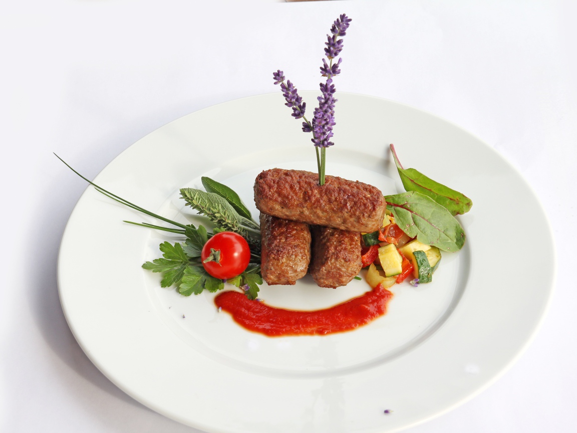 Meat sticks on a plate with herbs and sauce
