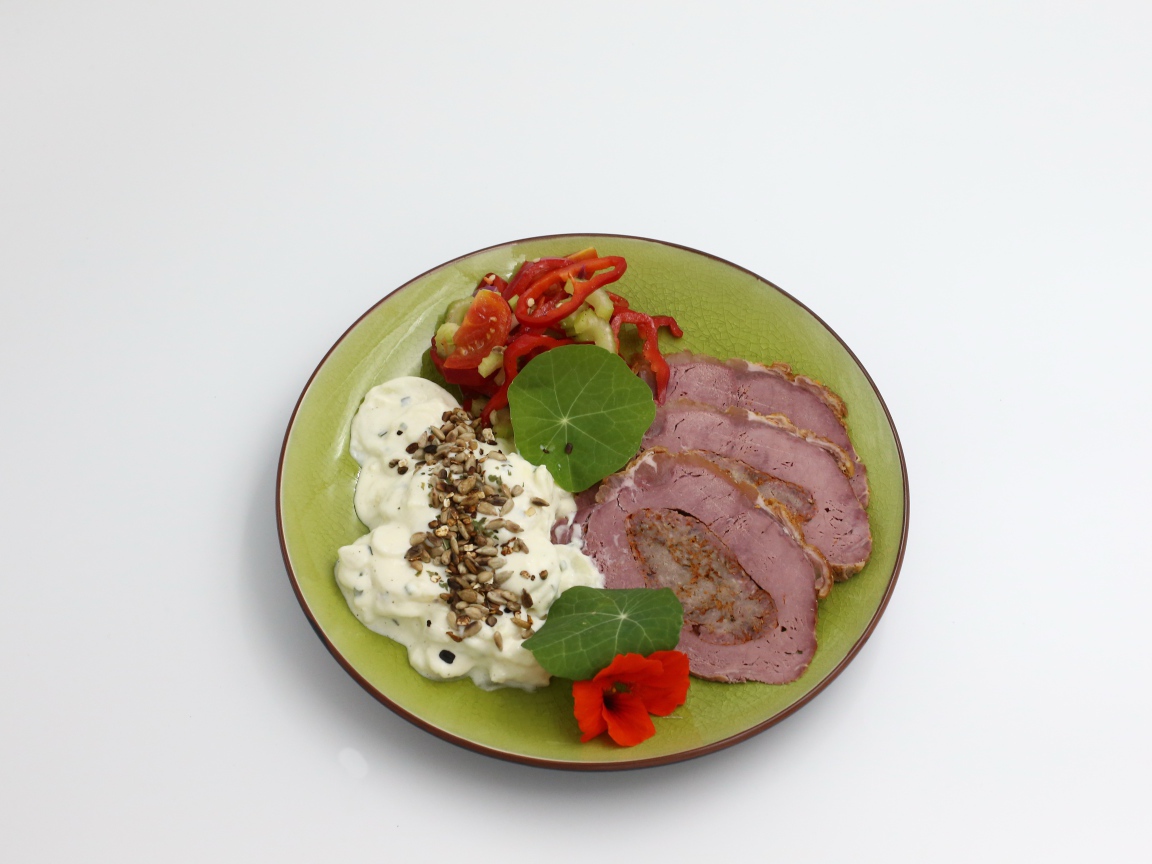 Мясо с соусом и овощами на тарелке на сером фоне