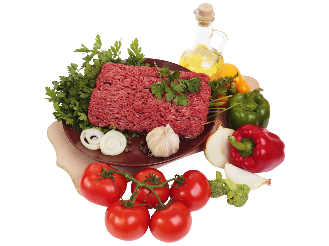 Minced meat on a white plate with vegetables and herbs