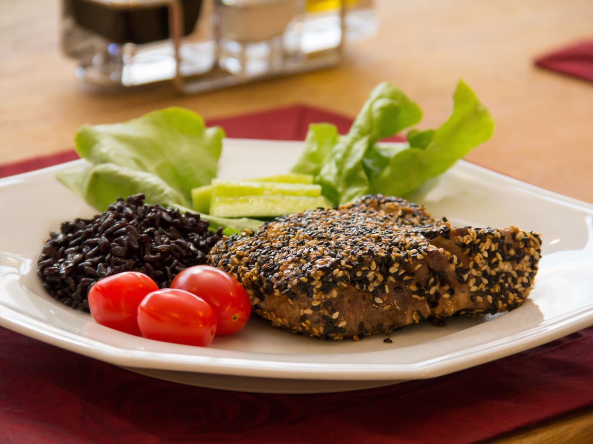 Кусок мяса на тарелке с рисом и овощами 