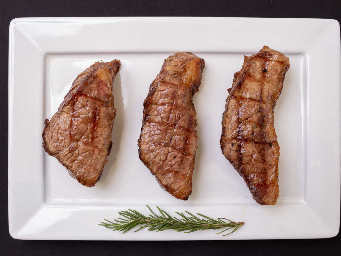 Три куска жареного мяса на большой белой тарелке