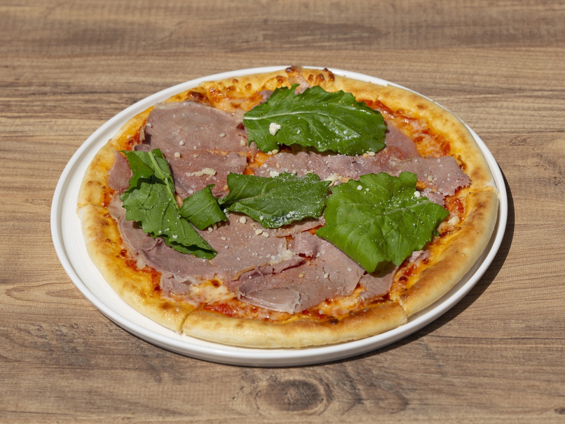 Пицца с кусочками мяса и зеленью на столе