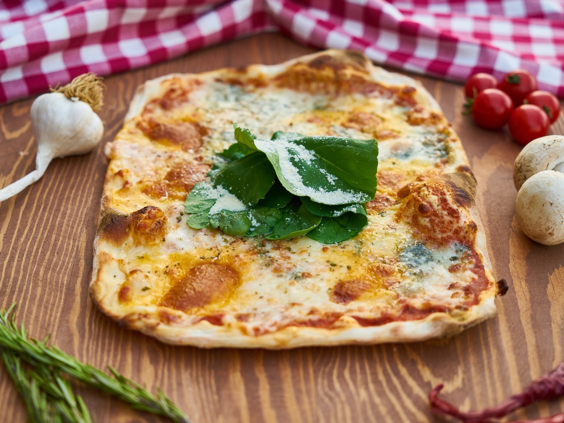 Румяная пицца на столе с овощами