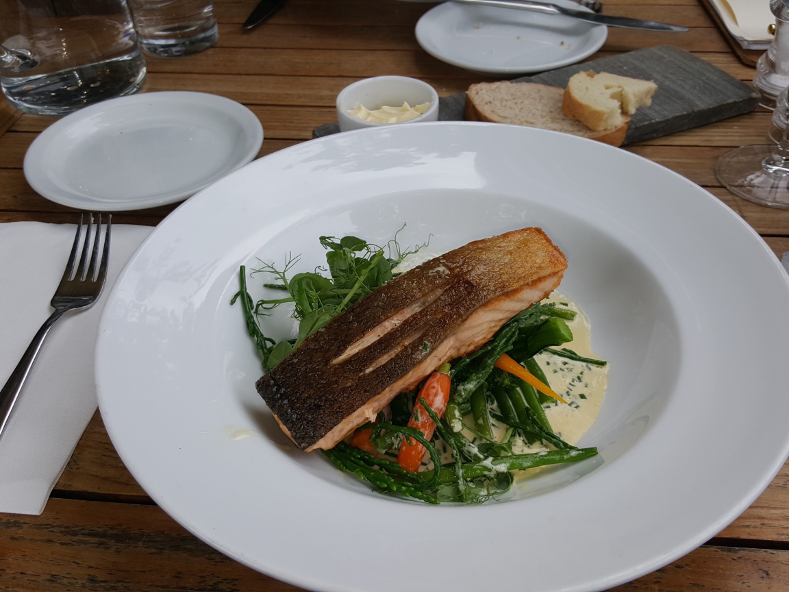 Кусок красной рыбы с овощами на столе в ресторане