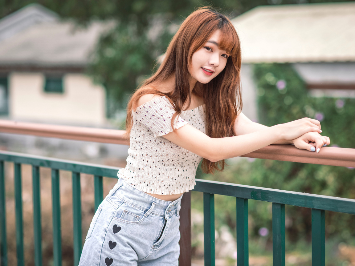 Красивая девушка азиатка стоит у перил у дома