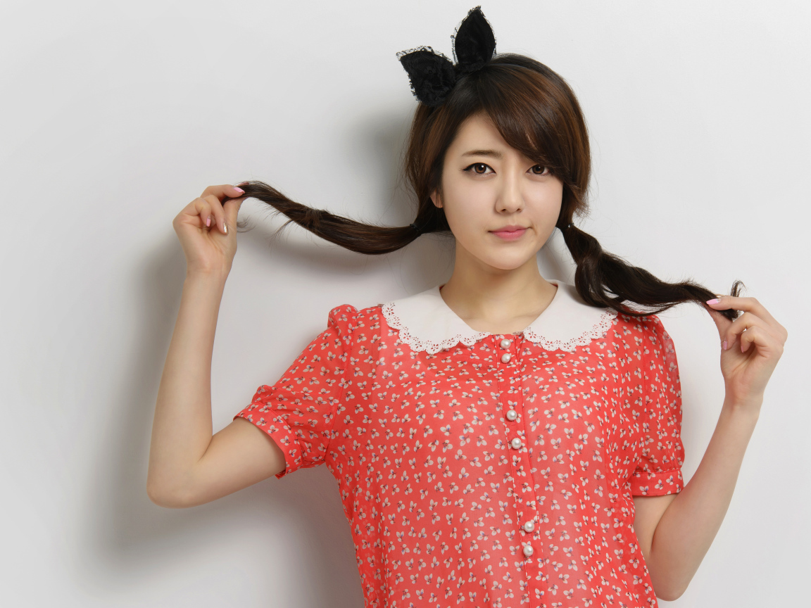 Девушка азиатка в платье стоит у стены 