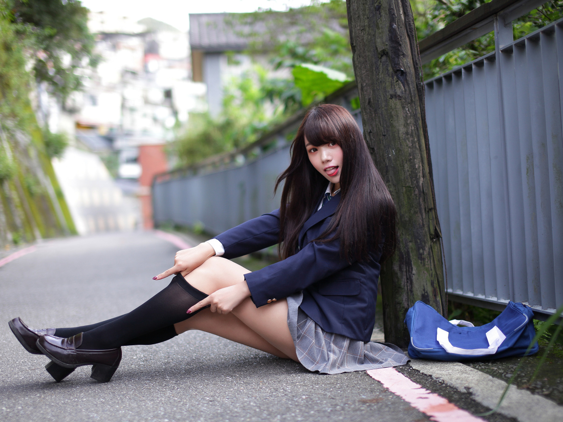 Девушка азиатка в черных чулках сидит у дерева