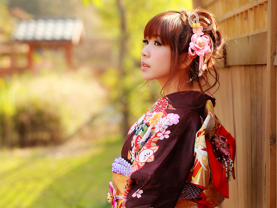 Asian girl in kimono stands at the fence
