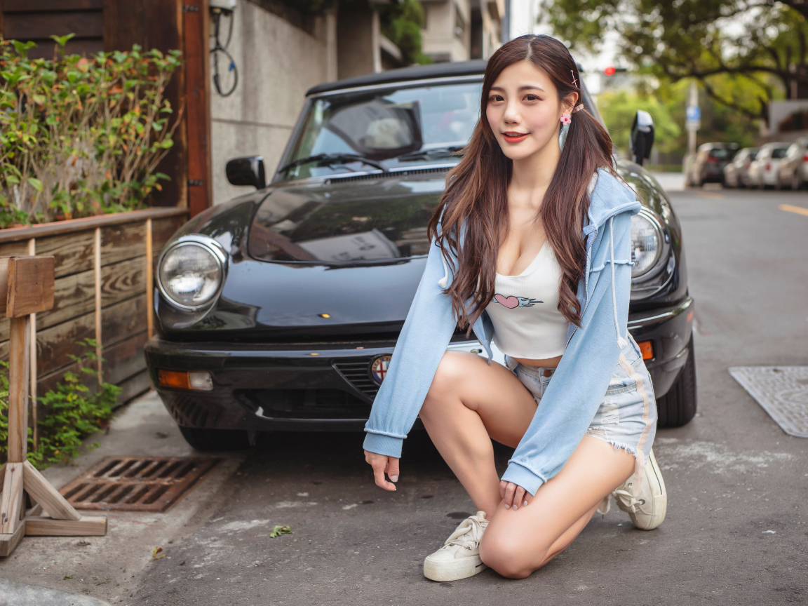 Девушка азиатка сидит возле машины 