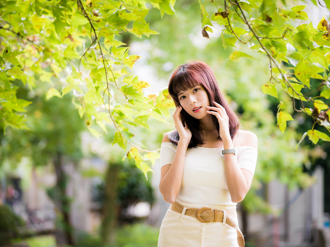 Красивая азиатка в белом платье у дерева 