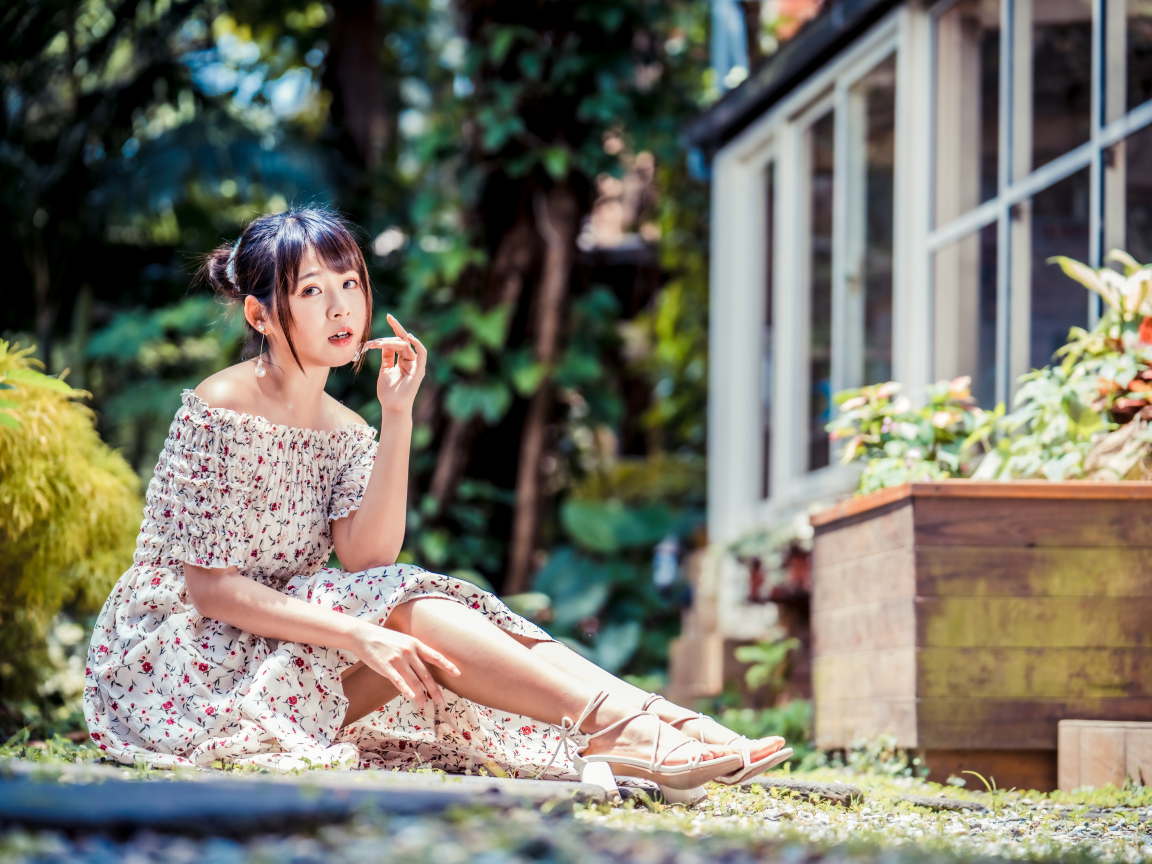 Красивая девушка азиатка в платье сидит на земле