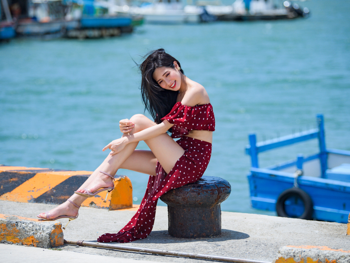 Красивая девушка азиатка в платье в горох у моря