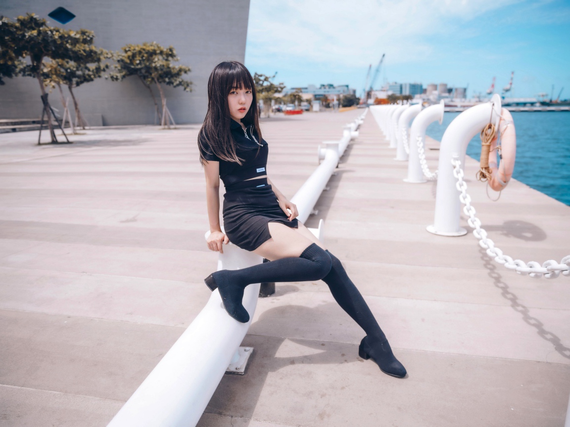 Красивая девушка азиатка в черных сапогах на причале