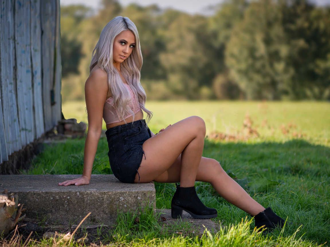 Красивая блондинка в черных шортах сидит на ступеньках 