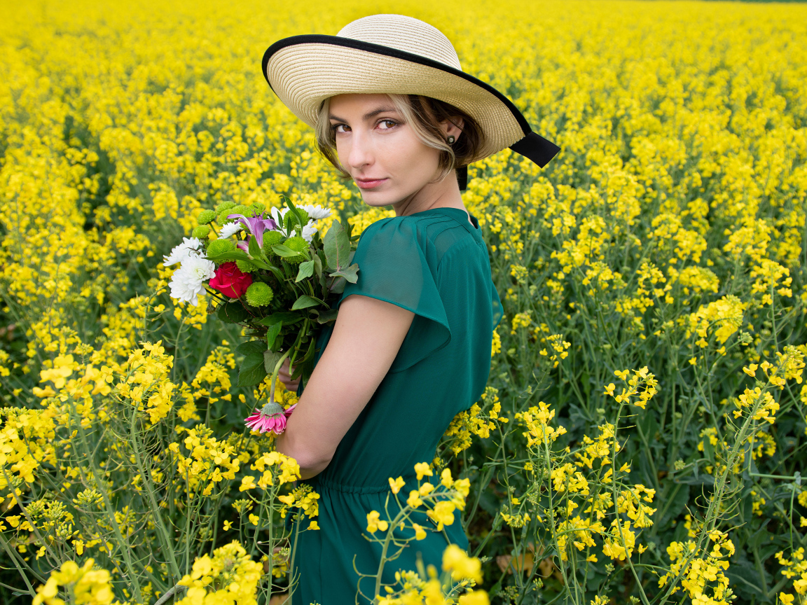Красивая девушка в шляпе на поле с желтыми цветами летом