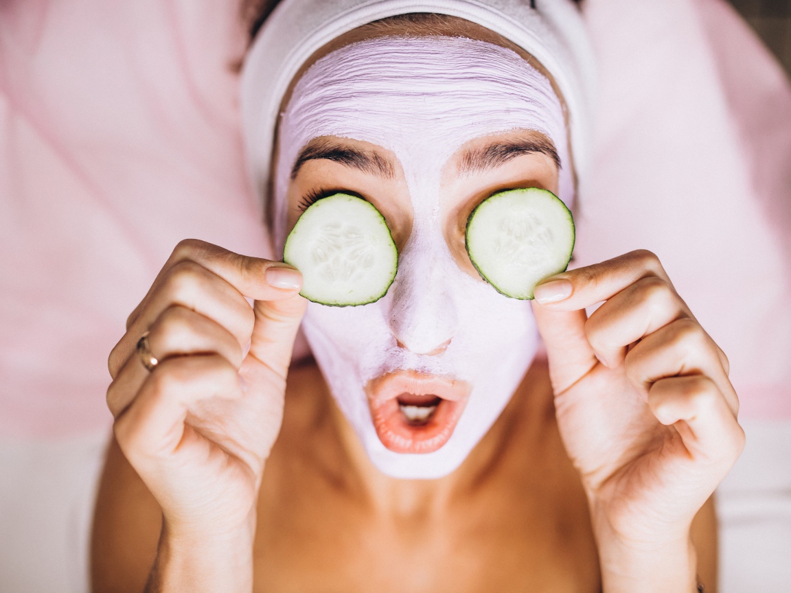 Девушка с маской на лице с огурцами на глазах 