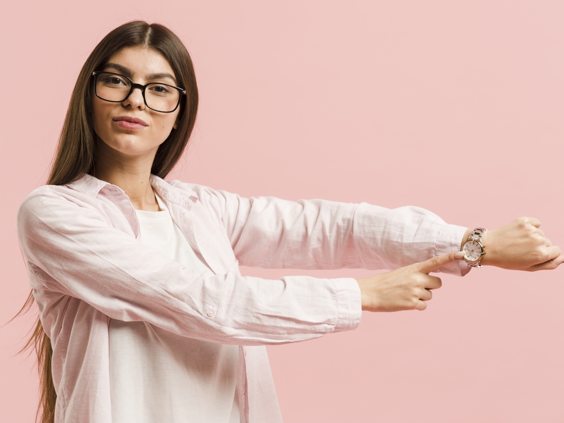 Girl with a watch on her hand on a pink background
