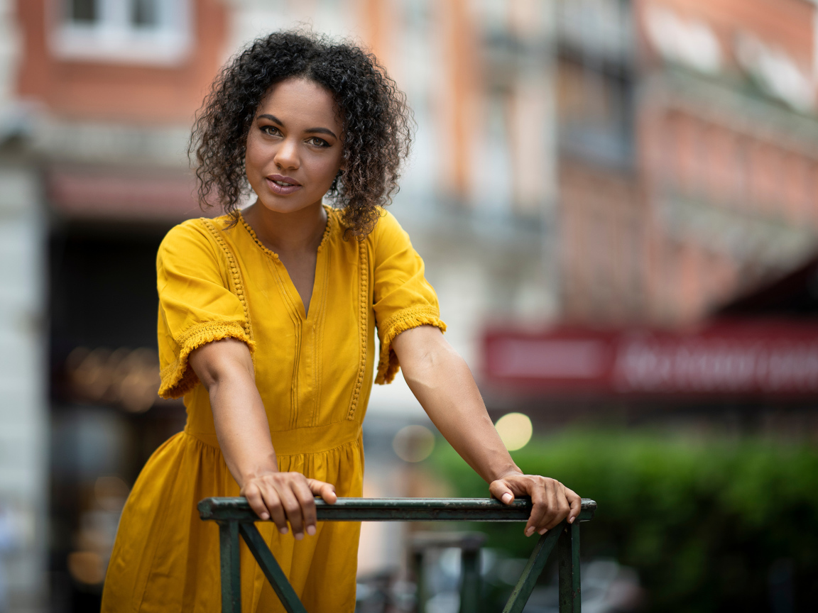 Девушка с кудрявым волосами в желтом платье