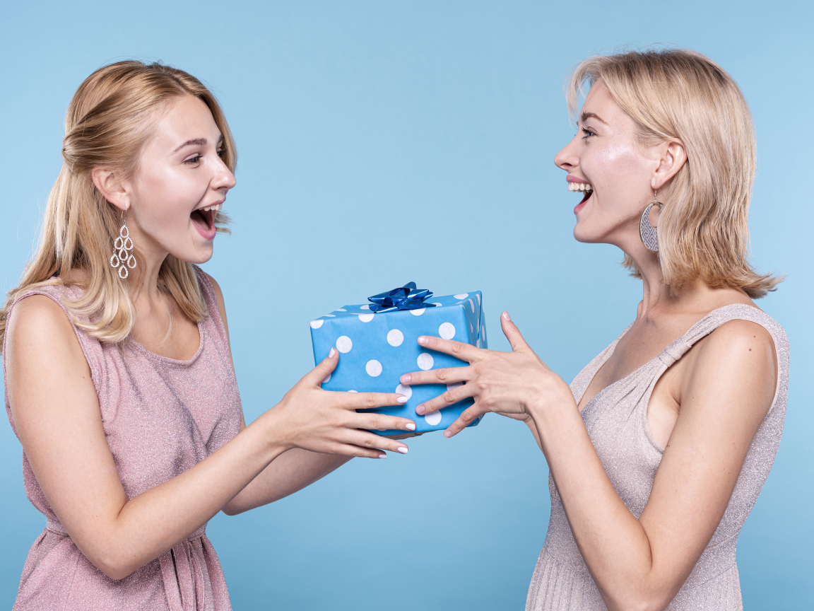 Две подруги блондинки с подарком на голубом фоне