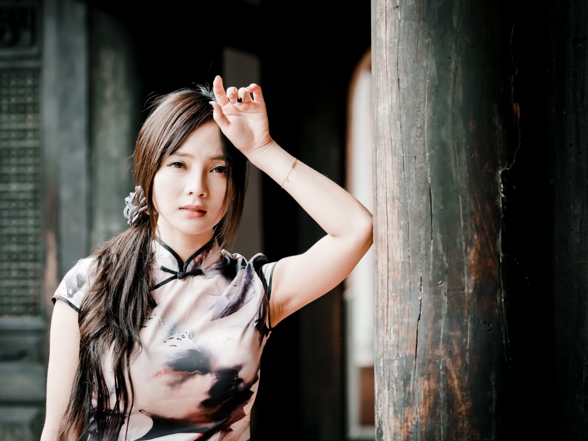 Молодая девушка азиатка стоит у столба 