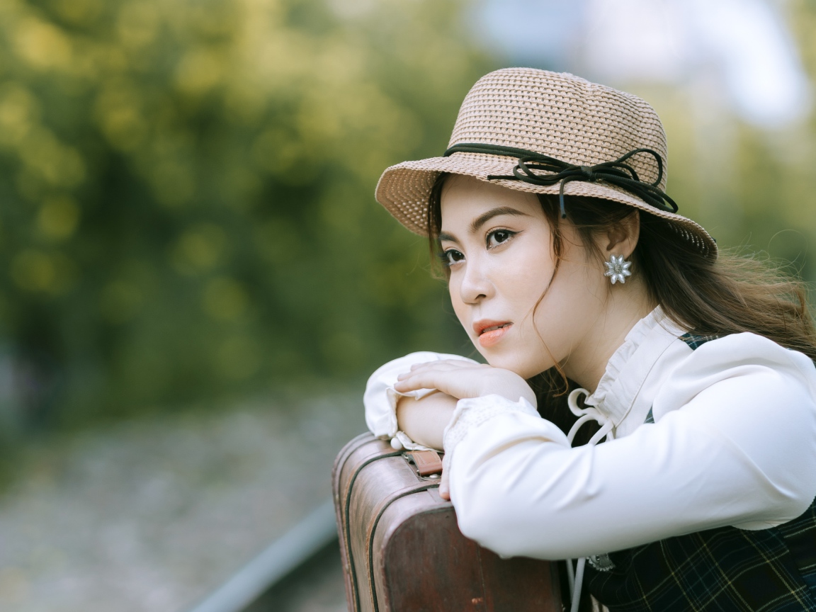 Молодая азиатка в шляпе с чемоданом