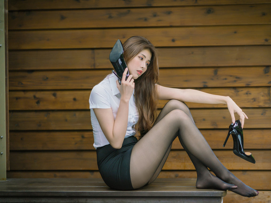 Молодая азиатка с черными туфлями в руках 