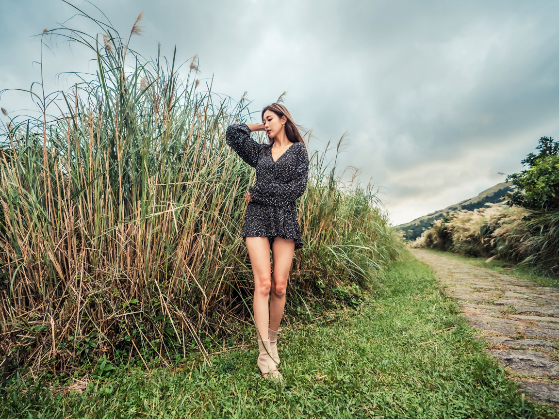 Молодая девушка азиатка стоит у зеленой травы