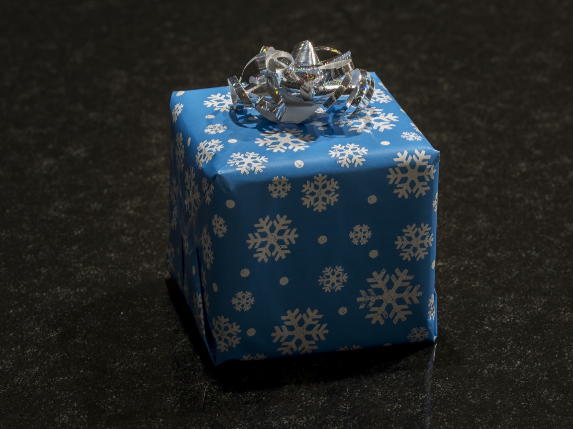 Big blue gift with bow on black background