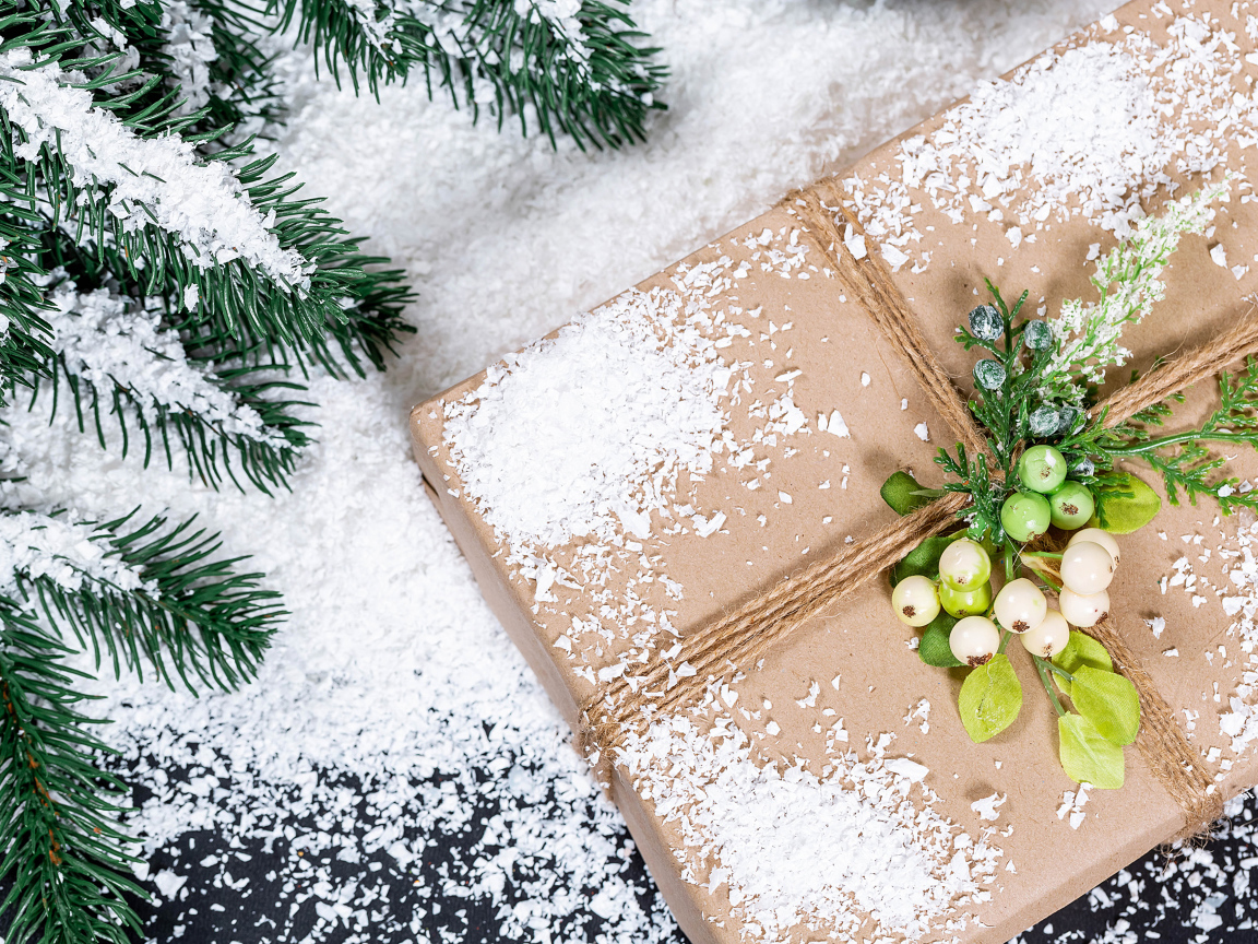 Подарок с заснеженной веткой ели на столе