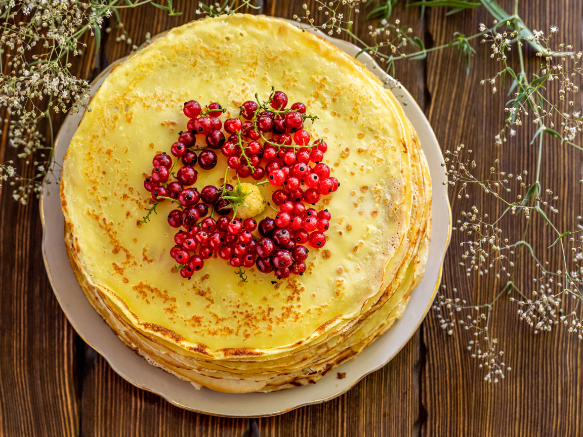 Аппетитные блины с ягодами красной смородины на столе 